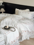Lightly washed cotton bedding set with ruffled border and fine floral embroidery