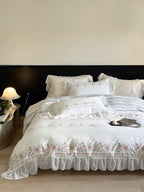 Lightly washed cotton bedding set with ruffled border and fine floral embroidery