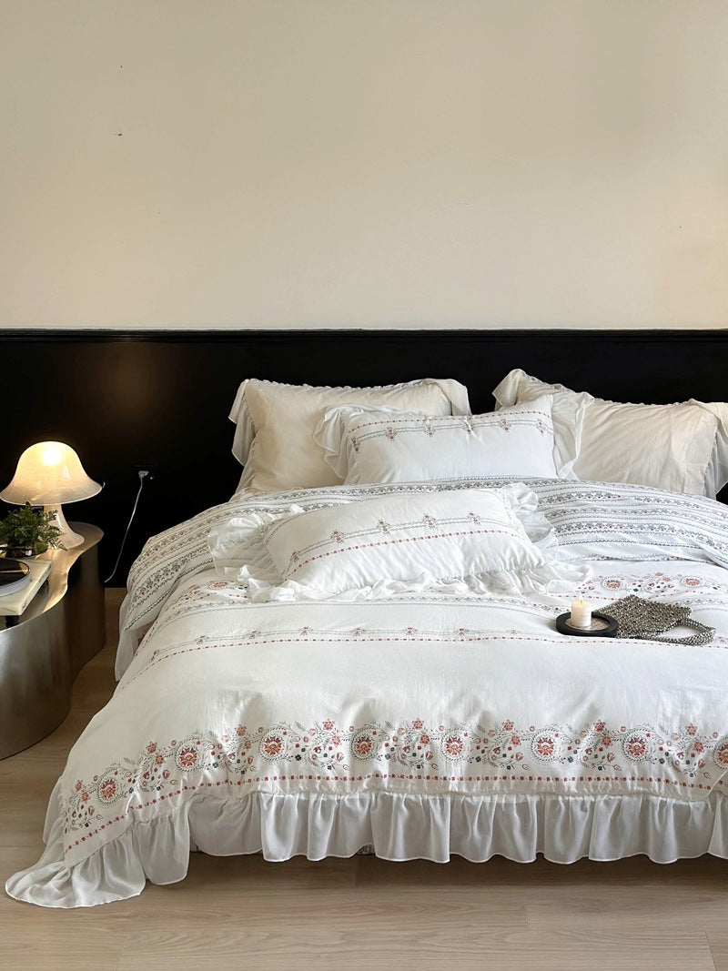 Lightly washed cotton bedding set with ruffled border and fine floral embroidery