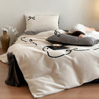 Reversible microfiber bedding set with plush surface, pom-pom corners, and paw embroidery