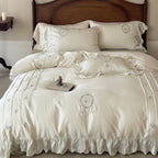 Satin bedding set with embroidered wreath motif, ruffled hem and decorative piping