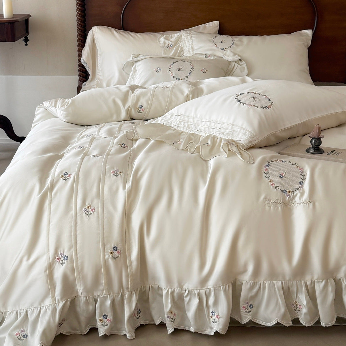 Satin bedding set with embroidered wreath motif, ruffled hem and decorative piping