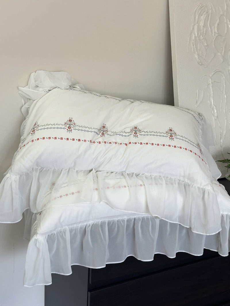 Lightly washed cotton bedding set with ruffled border and fine floral embroidery