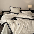 Luxurious satin bedding set with black lace trim and embroidered rose appliqués