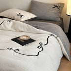 Reversible microfiber bedding set with plush surface, pom-pom corners, and paw embroidery